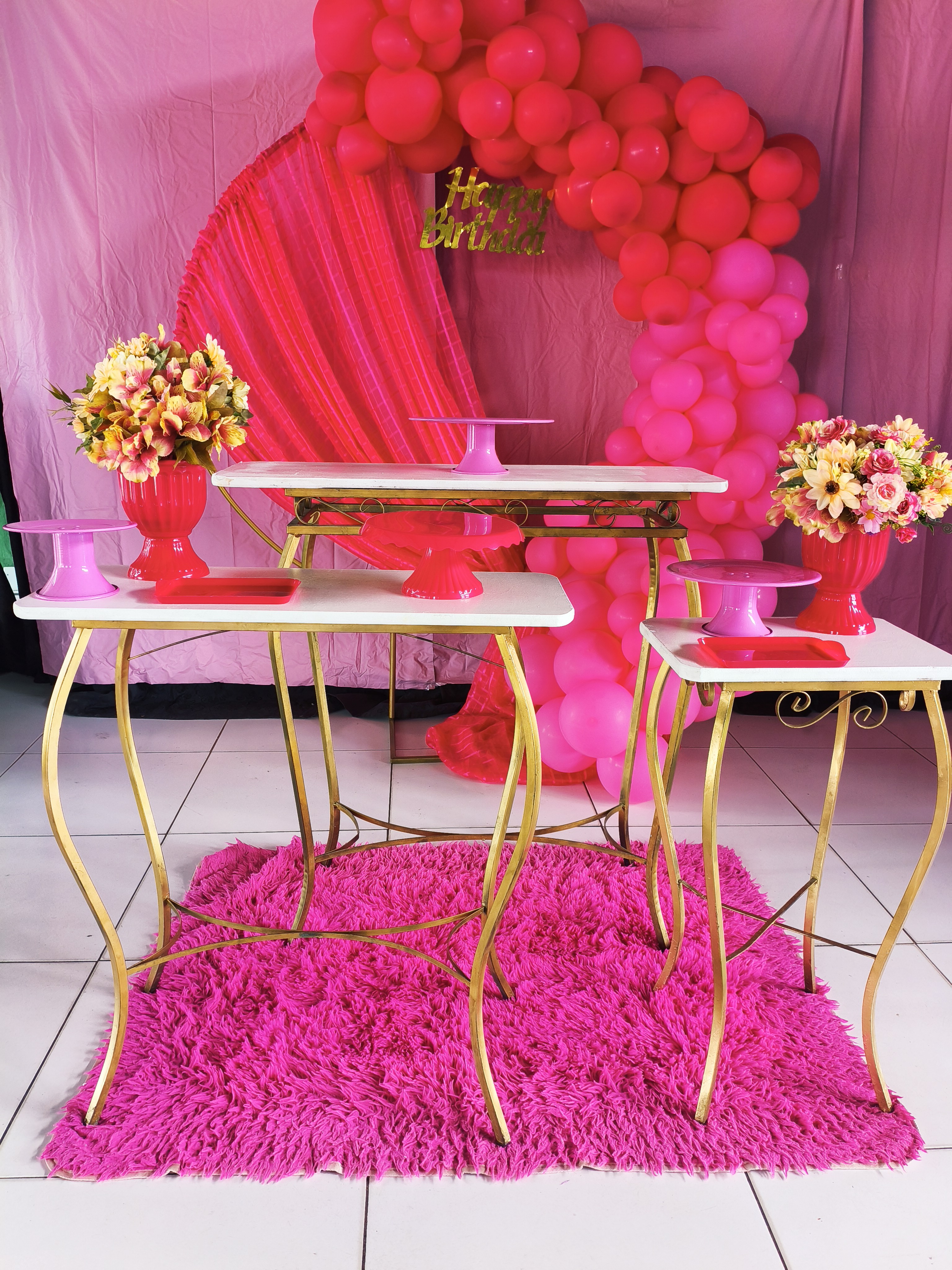 Decoração rosa com mesas douradas, flores e balões